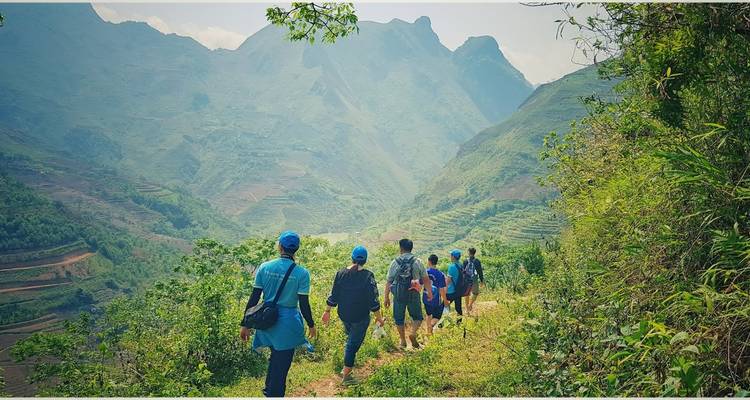 Group of hikers walking along a lush mountain trail, likely in Vietnam.