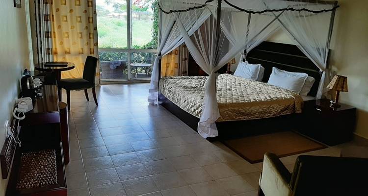 Amplia habitación de hotel con una cama con dosel y vista al exterior.