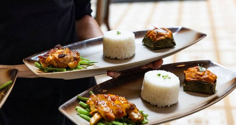 Platos de comida camboyana con arroz y verduras siendo servidos.