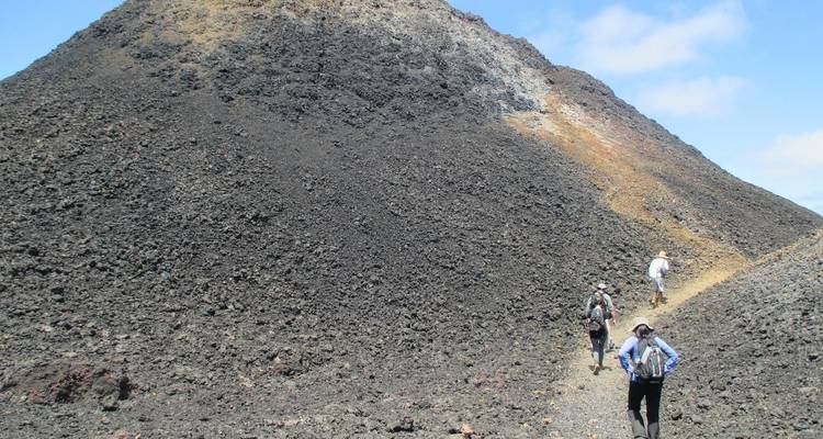 People hiking on a volcanic landscape.