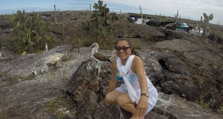 Woman posing with wildlife on rocky terrain.