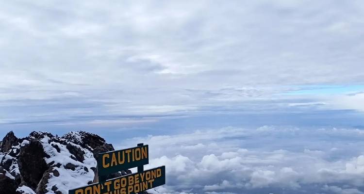 Blick aus großer Höhe über Wolken mit Warnschild.