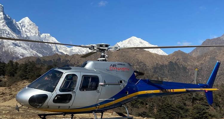 Hélicoptère avec des montagnes enneigées en arrière-plan.