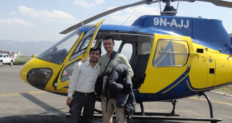 Deux hommes posant avec un hélicoptère bleu et jaune.