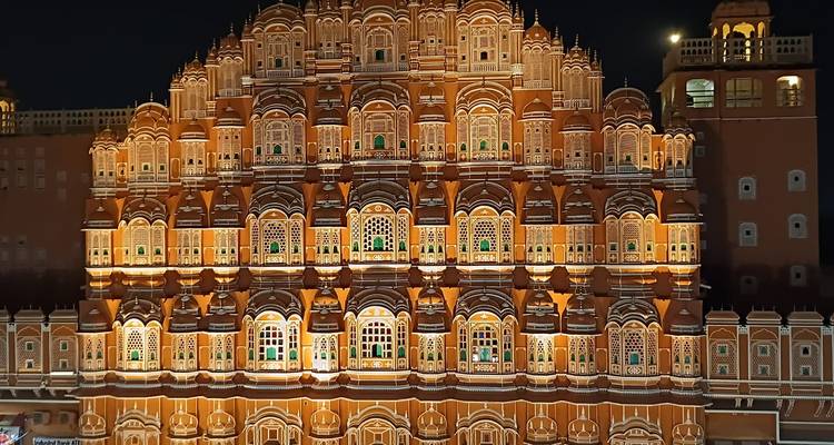 Nächtliche Beleuchtung des Hawa Mahal von Jaipur mit seiner kunstvollen Wabenstruktur-Fassade, die in Bernsteinfarben erstrahlt.
