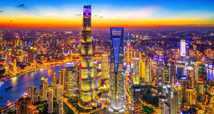 Coucher de soleil aérien des gratte-ciel imposants de Shanghai avec les lumières de la ville scintillantes le long du fleuve.