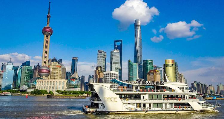 Un horizon urbain avec des gratte-ciel modernes et une rivière avec un bateau touristique.