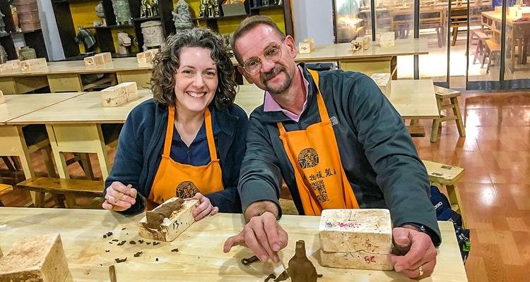 Deux personnes sculptant de petites sculptures à une table d'atelier.
