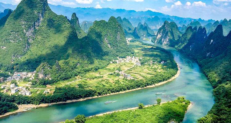 Une vue panoramique d'une rivière serpentant à travers des montagnes luxuriantes et escarpées.
