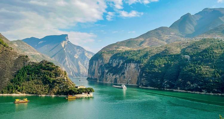 Los barcos de crucero navegan por las aguas verdes de la Garganta de Qutang rodeados de acantilados de piedra caliza que se elevan majestuosamente.