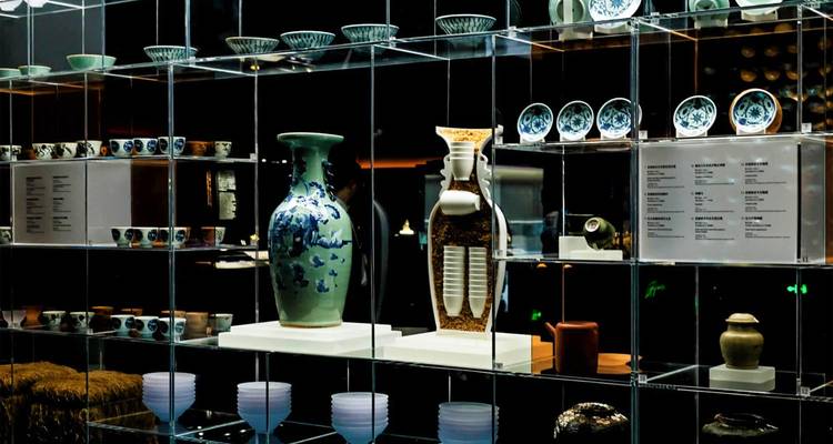 Exposition muséale intérieure de céramiques et porcelaines chinoises traditionnelles disposées avec soin derrière des étagères en verre transparent