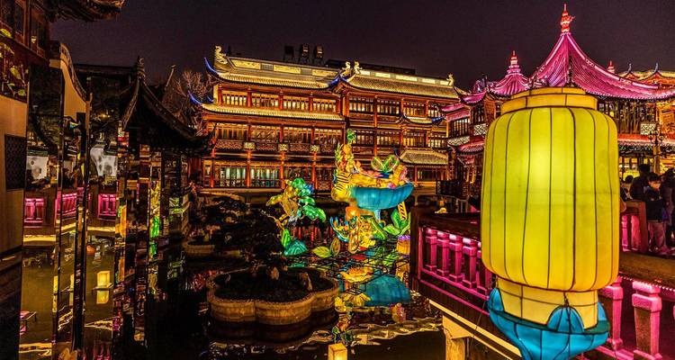Scène nocturne vibrante de bâtiments chinois traditionnels et d'installations de lanternes colorées se reflétant dans l'eau dans un cadre de festival