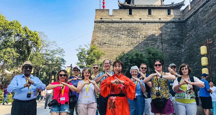A group of tourists posing joyfully in front of a historic wall.