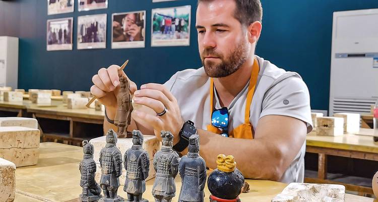 Ein Mann, der in einer Werkstatt Miniatur-Terrakotta-Krieger herstellt.