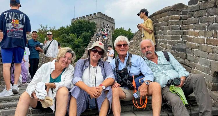 Tourists rest on a stone step of the Great Wall of China amid a crowd of visitors on an overcast day.