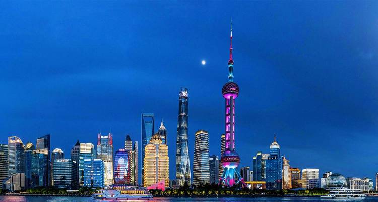 Iconic Shanghai skyline at blue hour featuring the illuminated Oriental Pearl Tower and sleek skyscrapers reflected on the Huangpu River.