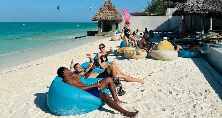 Personas descansando en puffs en una playa arenosa.