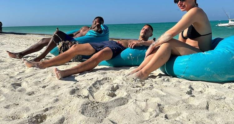 Personas descansando en una playa con vistas al océano.