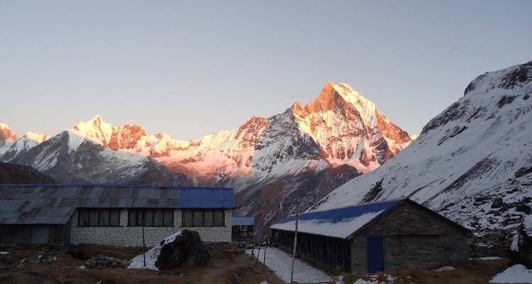 Sunlit mountain peaks with structures in the foreground.