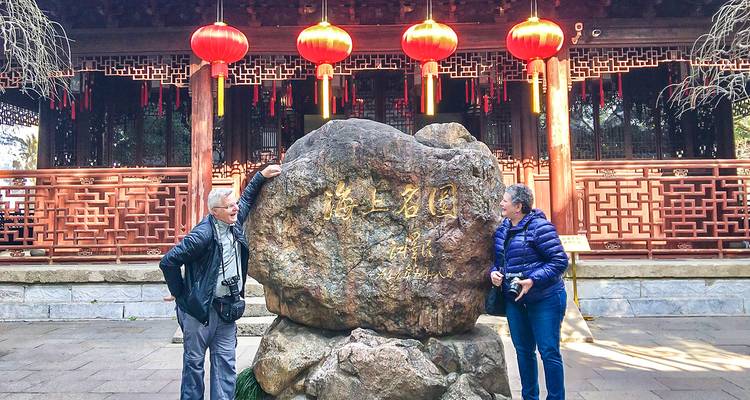 Zwei Personen stehen neben einem großen Felsen mit roten Laternen, die darüber hängen.