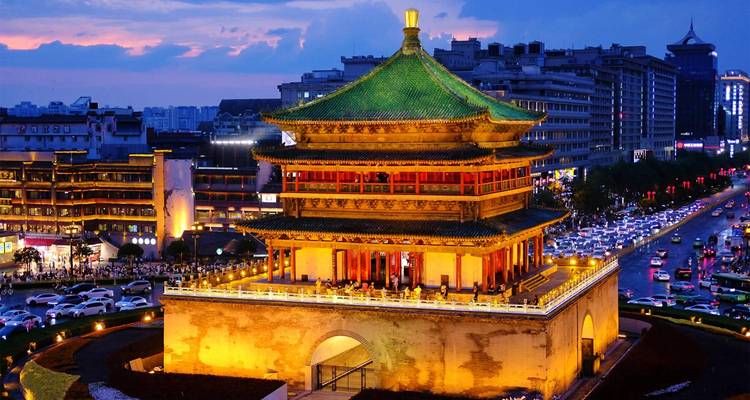 La Tour de la Cloche de Xi'an illuminée au crépuscule dominant le trafic intense et les lumières de la ville.