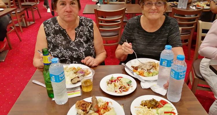 Twee vrouwen zittend met borden met eten op een tafel.