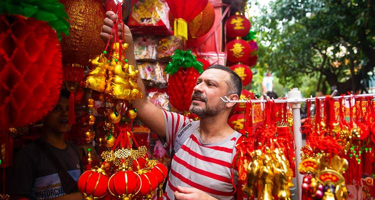 El comprador examina linternas y adornos rojo brillante y dorado en un puesto de mercado chino festivo.