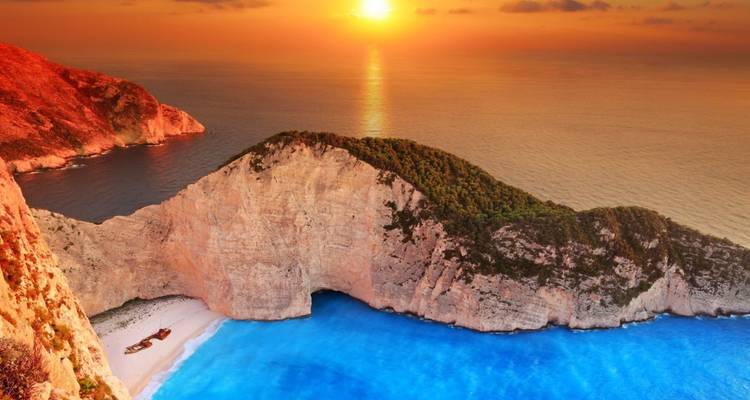 Vista del atardecer de la Playa Navagio con colores vibrantes sobre el mar.
