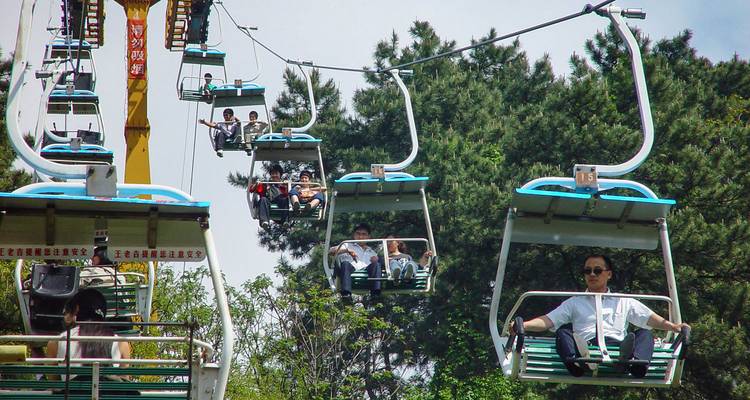 Teleféricos en un parque con gente montando.