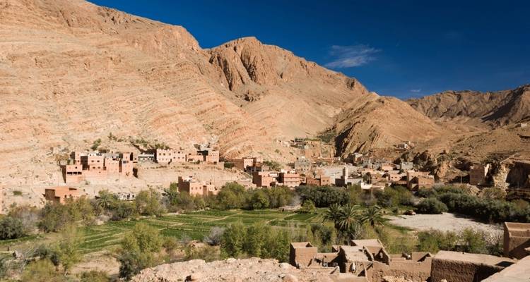 Bergdorf umgeben von üppigem Grün und felsigen Hügeln.