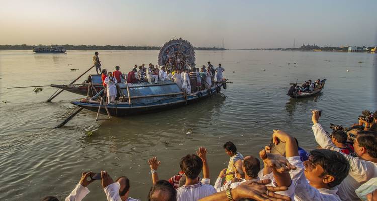 Group of people on a boat performing a ritual on a river.