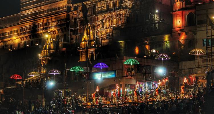 Een nachtscène met een menigte en verlichte gebouwen.