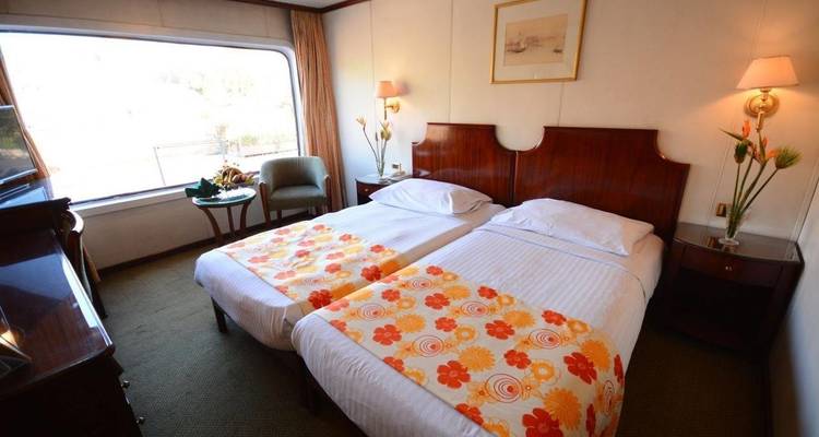 Innenraum eines Hotelzimmers mit zwei Einzelbetten und Blick nach draußen.