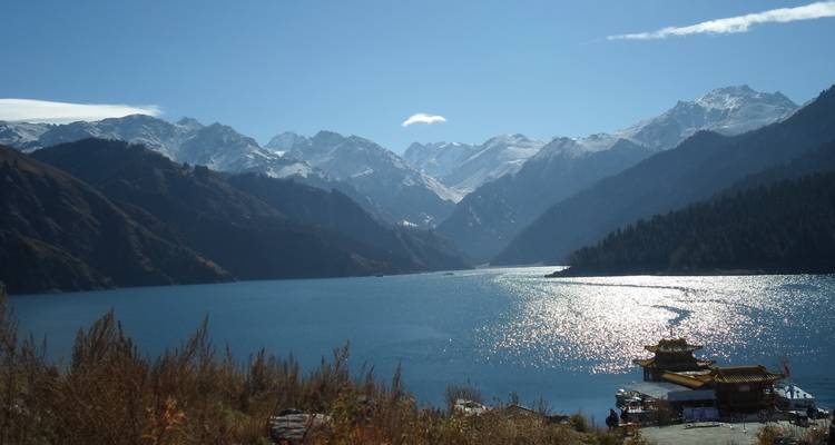 Ein ruhiger Bergsee mit der Spiegelung einer schneebedeckten Bergkette.