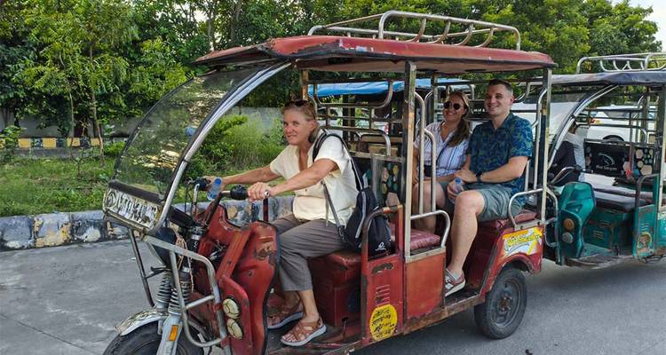 Zwei Personen auf einer Tuk-Tuk-Fahrt durch ein grünes Gebiet.