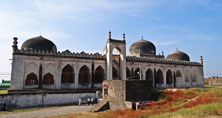 Historisches Gebäude mit Kuppeldächern und Bögen.