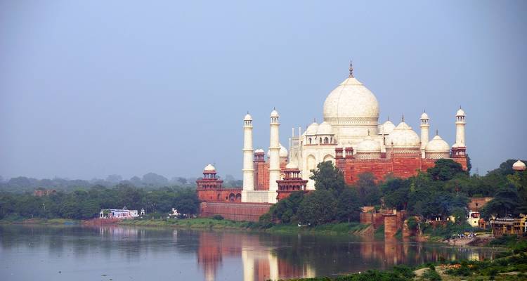 Taj Mahal by the river with clear reflections.