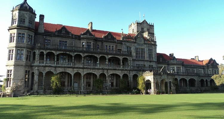 Historisches Herrenhaus mit üppigem grünem Garten und hellem Himmel.