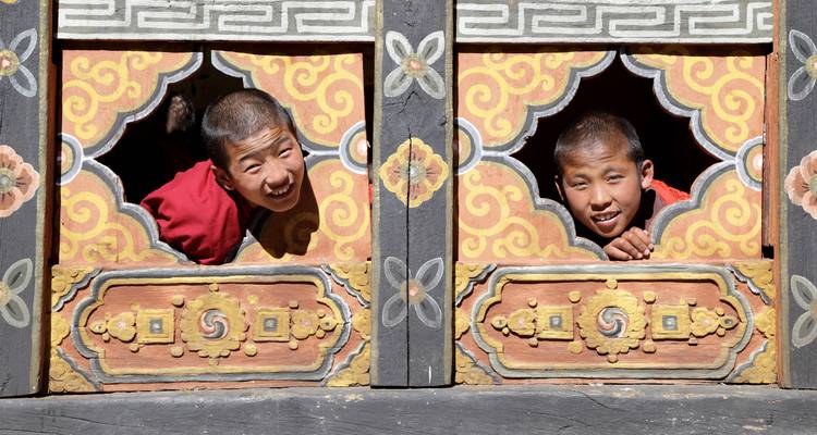 Dos niños asomándose por ventanas ornamentadas.