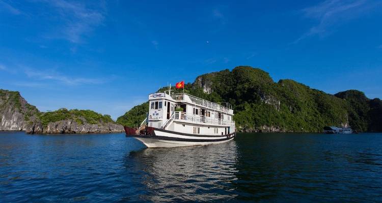 Bateau de croisière naviguant dans une baie pittoresque avec des îles verdoyantes.