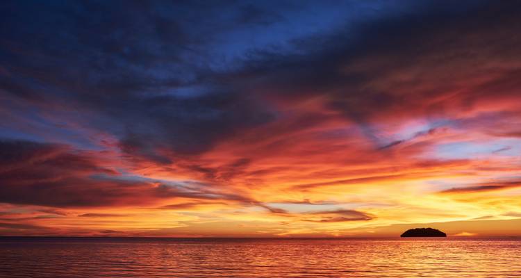 Coucher de soleil vibrant sur l'eau avec des nuages spectaculaires.
