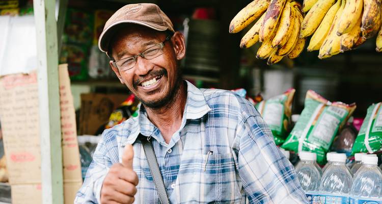 Homme souriant levant le pouce sur un étal de marché.