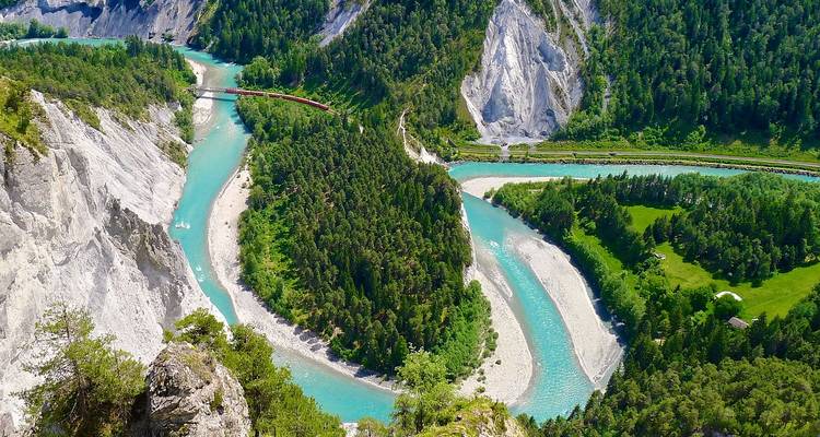Aqua-blue river winds through steep limestone gorge covered in dense forest seen from a high viewpoint.