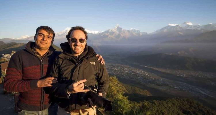 Twee mensen poseren met bergen op de achtergrond.