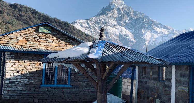 Besneeuwde berg achter traditionele stenen gebouwen.
