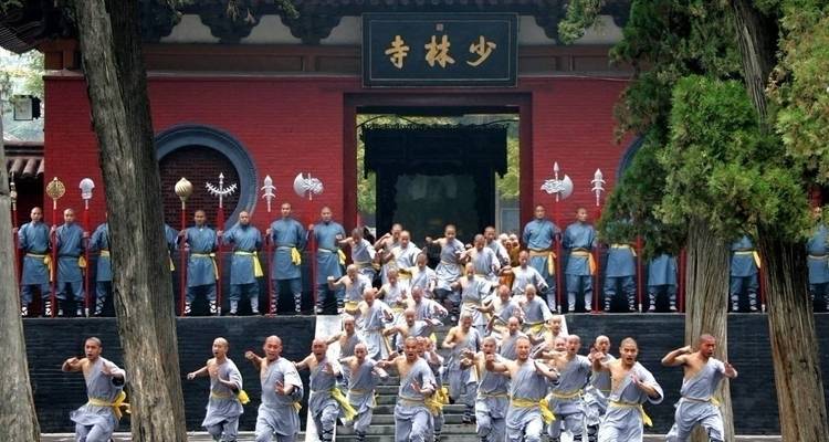Group of monks practicing martial arts in front of a building.