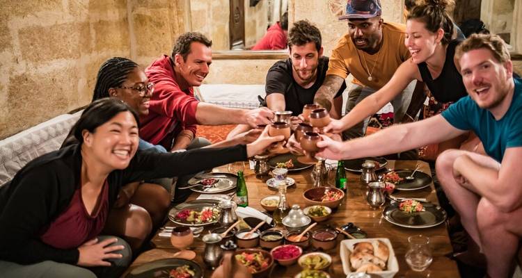 Groupe d'amis portant un toast avec des tasses traditionnelles lors d'un dîner entre amis.