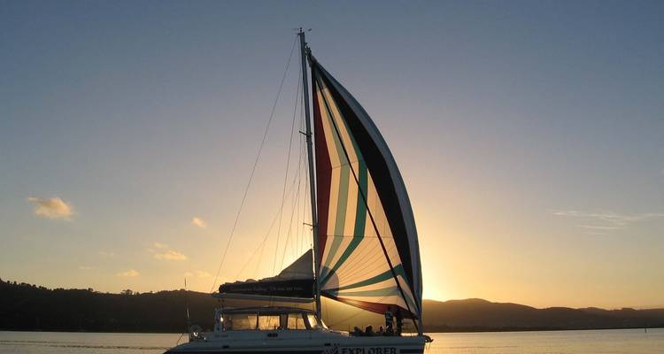 Velero con una vela colorida durante el atardecer.