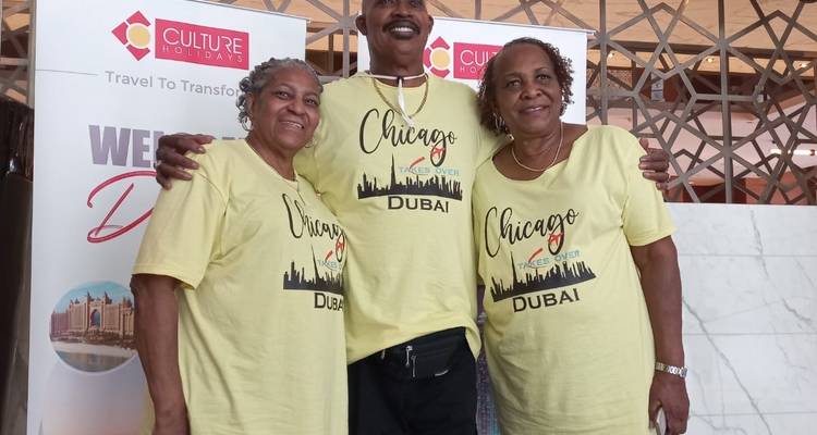 Drei Personen posieren vor einem Werbeschild.