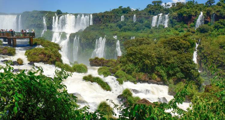 Stunning Iguazu Falls with lush green surroundings and tourists observing.
